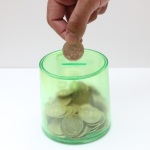 貯金箱にお金を入れようとしている様子