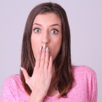 手を口にあてて驚いている若い女性