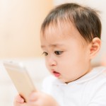 スマホを手に持って見ている赤ちゃん