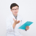 ファイルを見ながら質問をしている若い男性医師