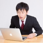 PCの画面を見て驚いているサラリーマン風の若い男性