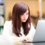 ノートPCの画面を見て操作をしている若い女性
