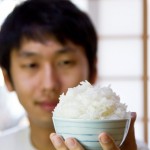 山盛りのご飯茶碗を持っている若い男性