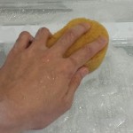 冷蔵庫の棚板を、洗剤を付けたスポンジでこすり洗いしている様子