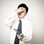 目頭を押さえている若いサラリーマン風の男性