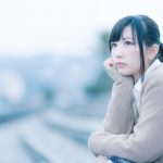 左手を頬にあてて考え込んでいる若い女性