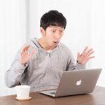PCの画面を見て驚いている若い男性
