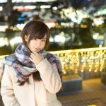 コートを着て、首にマフラーを巻いている若い女性