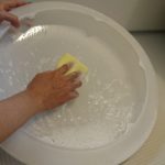 シーリングライトのカバーの内側を、食器用中性洗剤を含ませたスポンジでこすり洗いしている様子