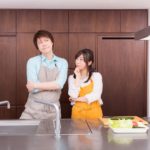 キッチンで考え込んでいるエプロンを付けた若い男女
