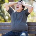 頭を押さえて困っている様子の若い男性