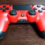 机の上に置かれているPlayStation4の赤いコントローラー DUALSHOCK 4
